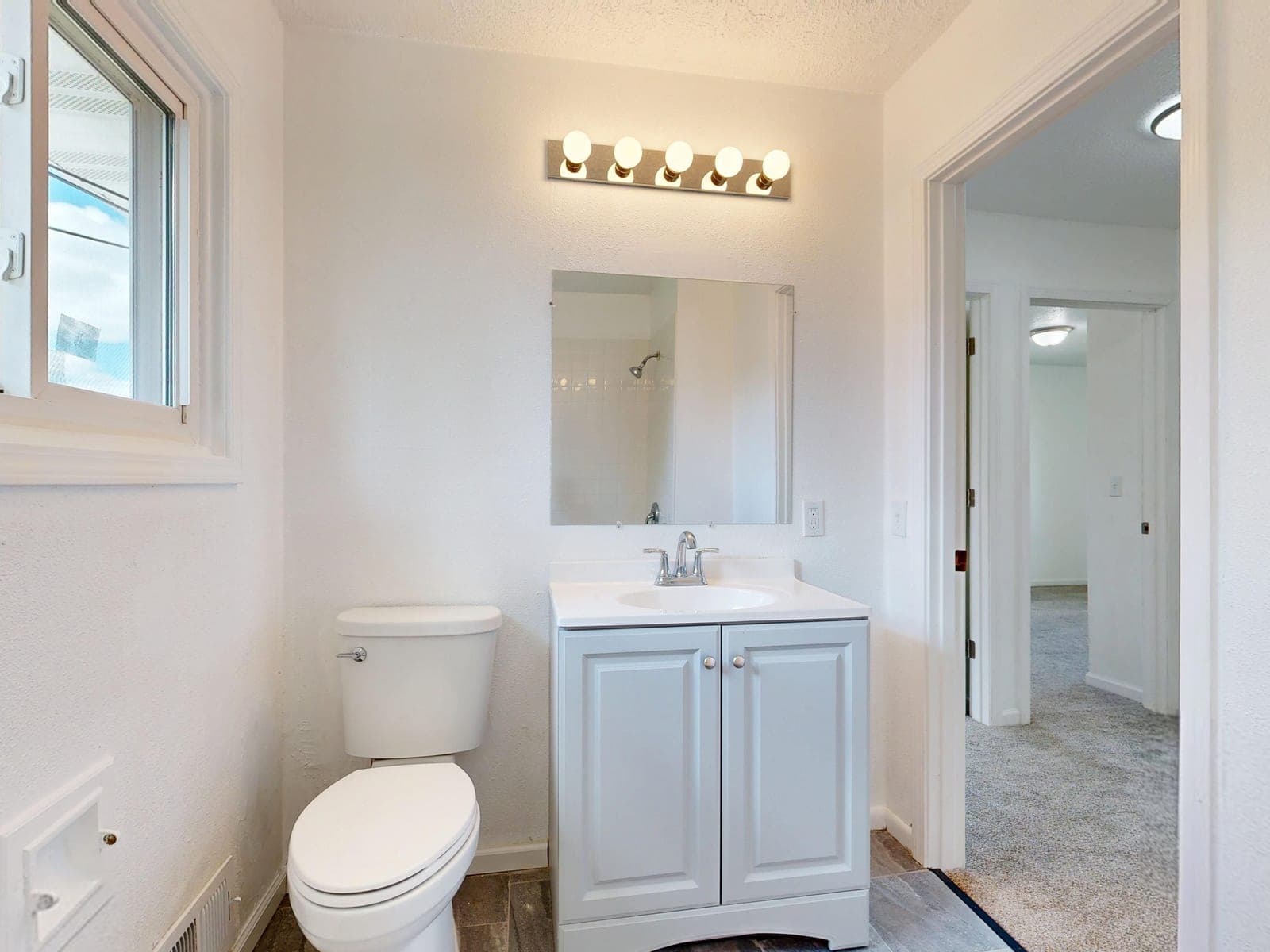 A clean, modern white bathroom with a toilet in natural daylight