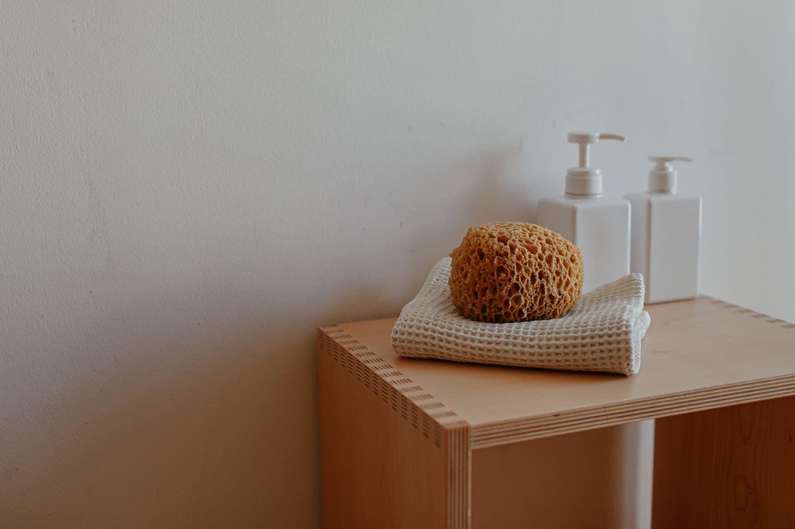A minimal bathroom shelf with folded towels and a hook