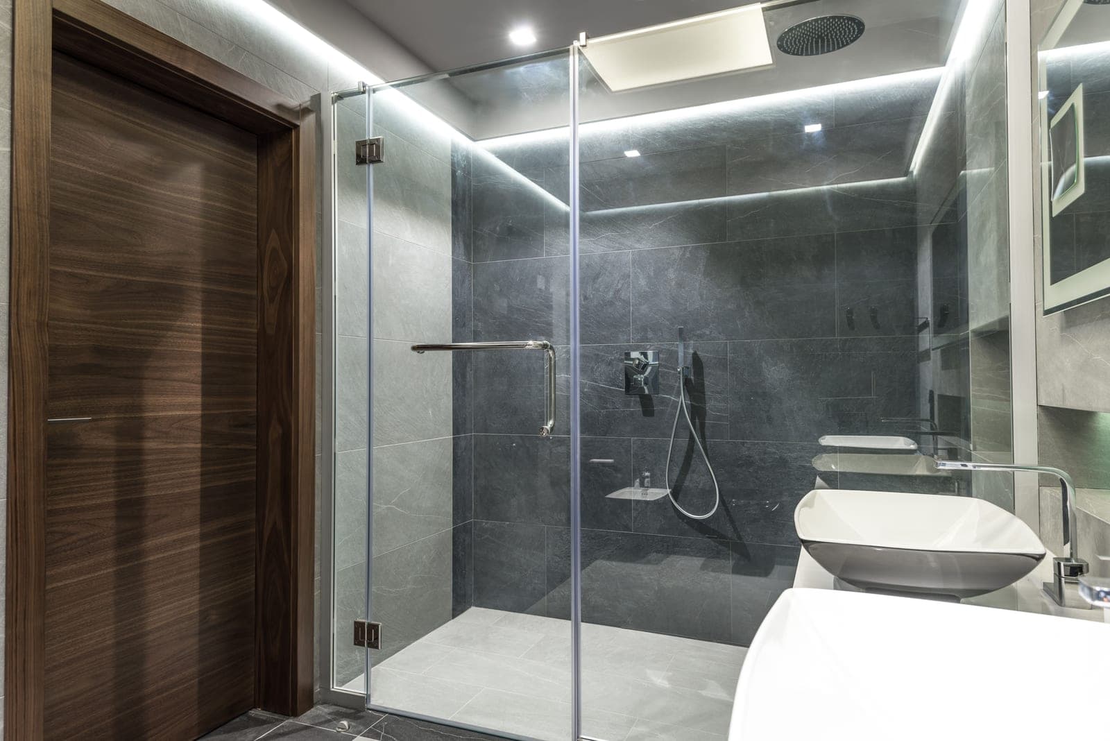 A bright walk-in shower with glass screen and pale tile