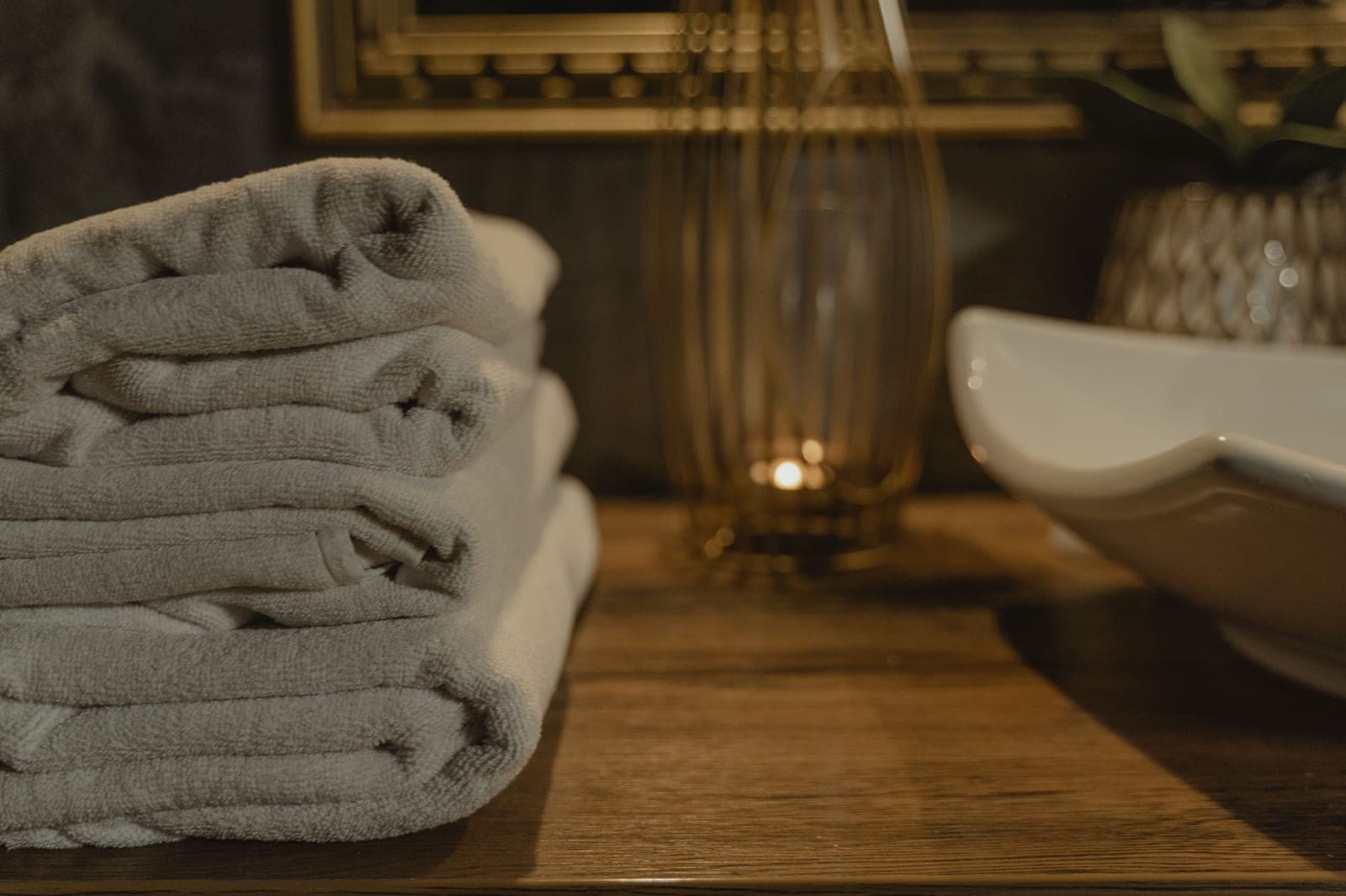 A stack of folded white towels in warm bathroom light